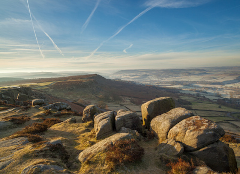A moorland image of The Pennines. Large boulders lie on Moorland below a clear winter sky.
