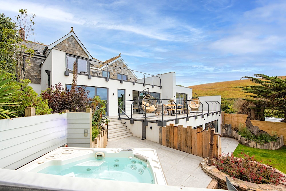 A contemporary house with a wrap-around deck overlooks a spacious garden with a large hot tub.