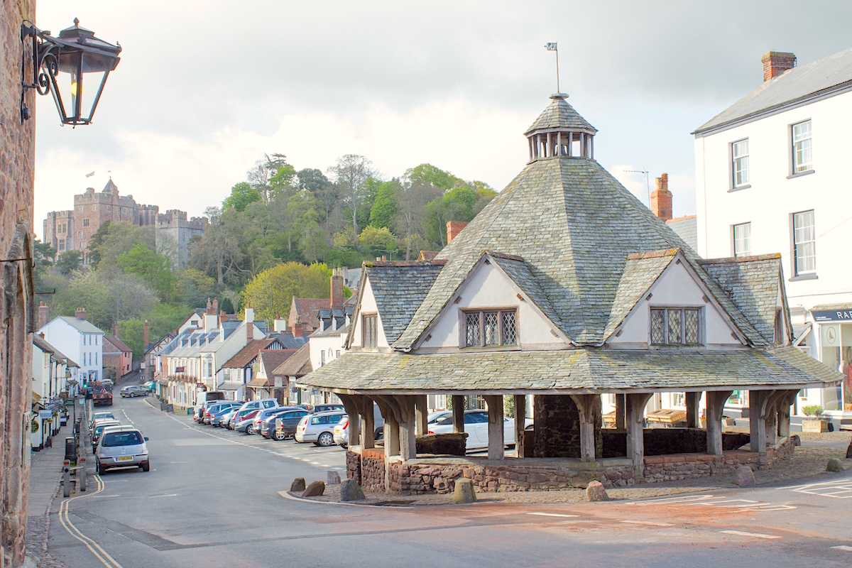 The yarn market in Dunster at the head of a shop-lined street. In the background, overlooking the street is Dunster castle.