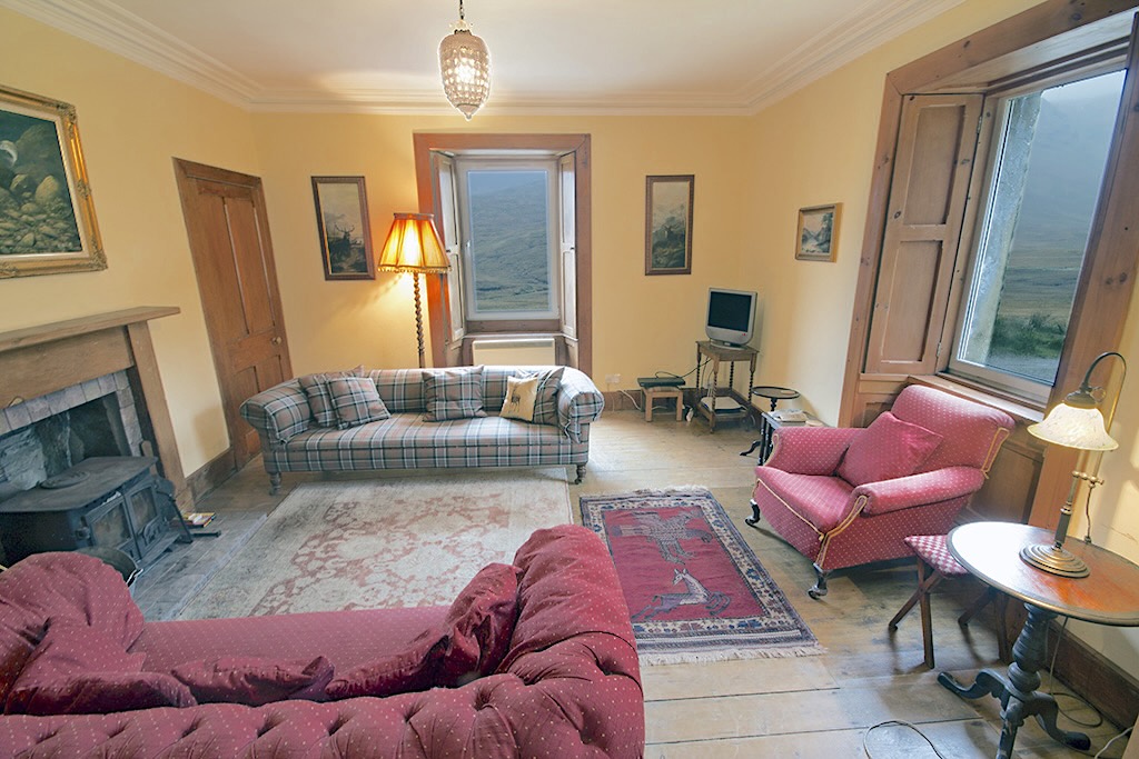 The lounge at Glenuaig Lodge with sofas, armchair and a wood burner.