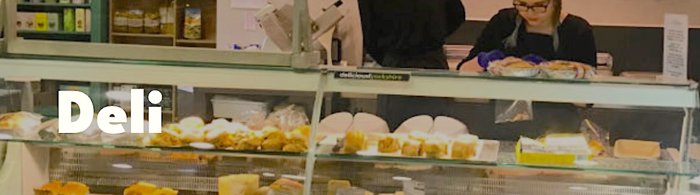 Front counter of Cedar Barn Deli with a glass case filled with cheeses and pies.