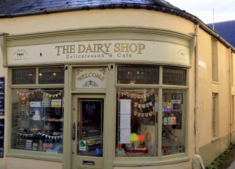 The shop front for The Dairy Cafe in Sidmouth with large windows displaying local produce.