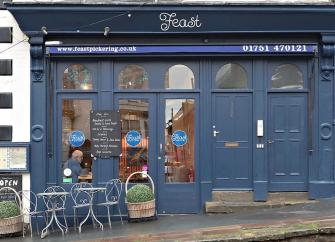 Feast cafe shop front in Pickering with large windows through which tables and chair can be seen