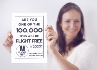 A woman holds up a Flight Free pledge certificate.