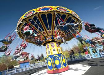 A colourful chair-o-plane, a vintage fairground ride spinning  round people in chairs.