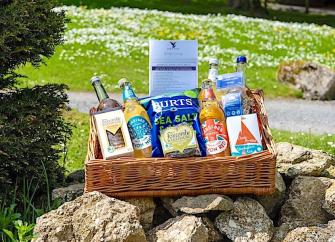 A welcome pack of food and drink in a wicker basket on a rocky garden cairn.