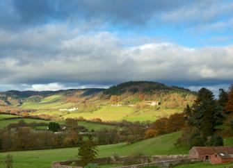 A landscape view of the Wye Valley at dusk with trees and open fields.