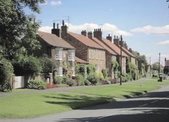 A row of stone-built cottages overlook a village green in Sutton-on-the-Forest.