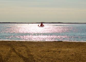 A sailing boat silhouetted against sunlit waves off Instow Beach in North Devon 