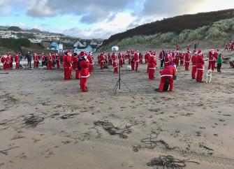 Santa Claus's limber up for the start of a Santa Fun Run on Woolacombe Sands in North Devon