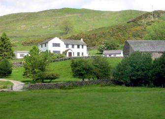 a Cumbria holiday cottage at the foot of a hill surrounded by fields and mature trees