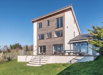 Modern, 3-storey Dorset eco-lodge overlooking a patio and large lawn.