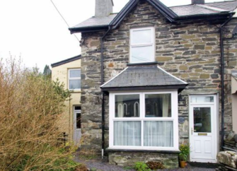 exterior of a stone-fronted holiday cottage in Snowdonia with a slate r.oofed bay window