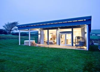 A contemporary glass-fronted eco-lodge with a hot tub and large garden.
