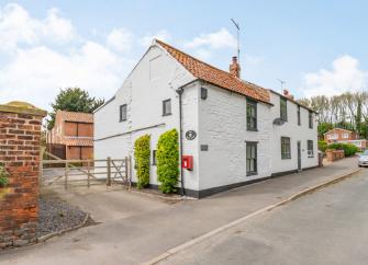 Exterior of a semi-detached holiday cottage in East Yorkshire overlooking a quiet road with plenty of parking spaces to the rear.