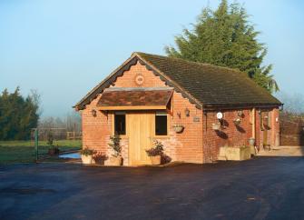 Exterior of a brick-built barn conversion surrounded by open countryside