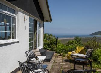 Gable end of a Somerset holiday bungalow with a terrace offering far-reaching views across fields and ocean at Porlock Bay
