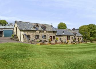 Exterior of a stone-built Exmoor Holiday Cottage surrounded by spacious lawns.