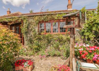 A single storey stone cottage overlooks a flower-filled garden 