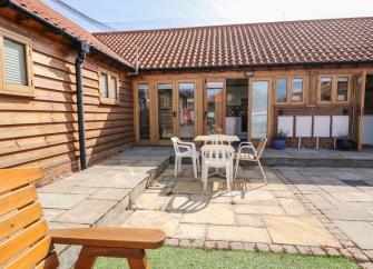 Exterior of a Hunstanton holiday cottage ovrlooking a paved courtyard with outdoor dining furniture
