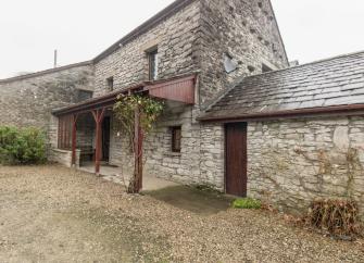 A stone, Cumbrian barn conversion in with a sheltered terrace overlooks a large parking space.