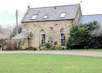 Exterior of a Peak District holiday cottage overlooking a large lawn.