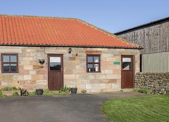 A single-storey North Yorkshire barn conversion with small lawn and drive.