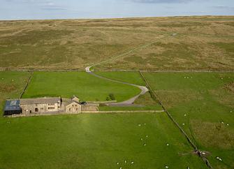 An isolated Pennine farm house is surrounded by empty moorland.