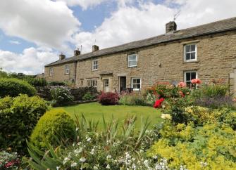 A stone-built terrace of cottages with flower-filled gardens in Swaledale.