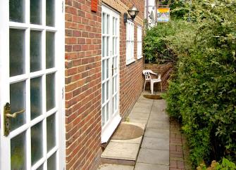 A paved path leads to the side entrance of a brick built, Isle-of-Wight holiday cottage 
