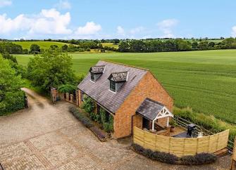 A Northamptonshire barn conversion with a paved courtyard surrounded by open fields.