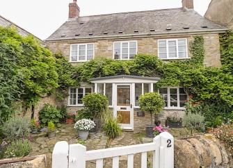 Exterior of a double-fronted, wisteria-clad Abbotsbury holiday cottage