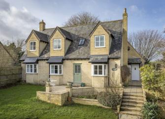 Exterior or a modern Cotswold honeystone house with triple bay windows