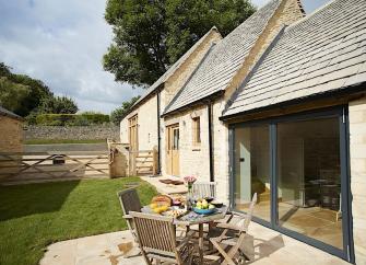 A side elevation of a Cotswold Barn conversion with wide full-height sliding French Windows.