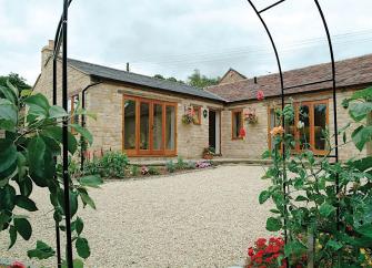 L-shaped single-storey exterior of a Warwickshire holiday cottage overlooking a courtyard.