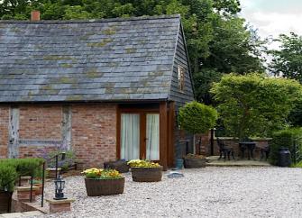 A Shropshire barn conversion with French windows and flower tubs in the shingled garden