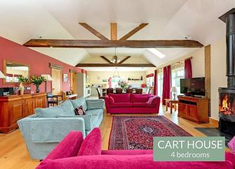 A large open plan lounge with beamed ceiling, widescreen TV and comfy sofas.