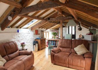 A cottage lounge with a pine-beamed ceiling and comfortable leather sofas.