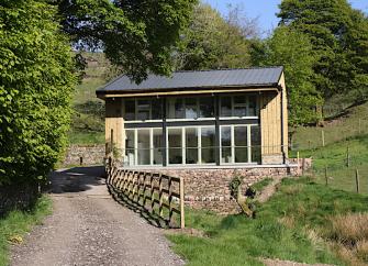 Exterior of a contemporary country cottage with a full-width balcony and floor-to-ceiling sliding glass doors.