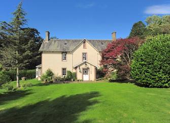Exterior of a Scottish Manse overlooking s large tree-line lawn