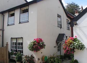 2-Storey cottage exterior with hanging flower baskets.