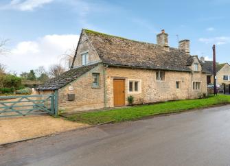 A honeystone Cotswold cottage overlooks a village street.