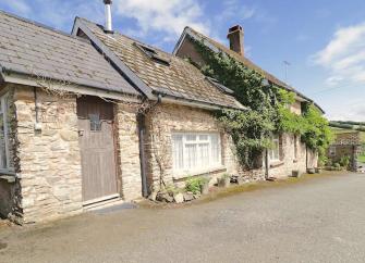 A wisteria-clad stone cottage on Exmoor with a solid oak door