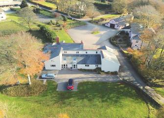 Aerial view of a large Exmoor farmhouse and farm yard surrounded by fields.