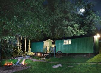 Two shepherd huts at dusk, converted and linked to form a single unit.