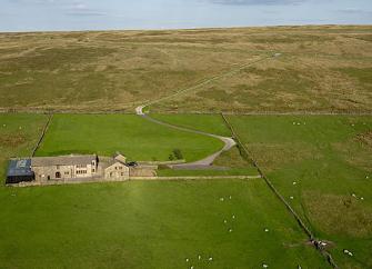 Aerial view of farm buildings on a remote Pennine hillside.