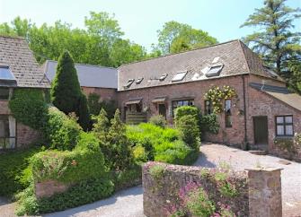 exmoor barn conversion overlooks a shrub-filled garden and drive.