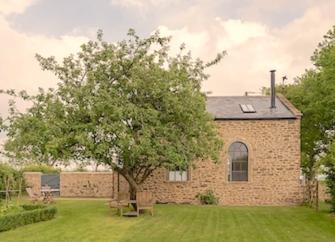 A Somerset barn conversion, partially obscured by a tree.