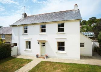 A double-fronted East Devon holiday cottage in front of a secure lawned garden.