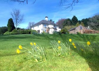 Large country cottage in Watchet overlooking a daffodil-filled lawn.